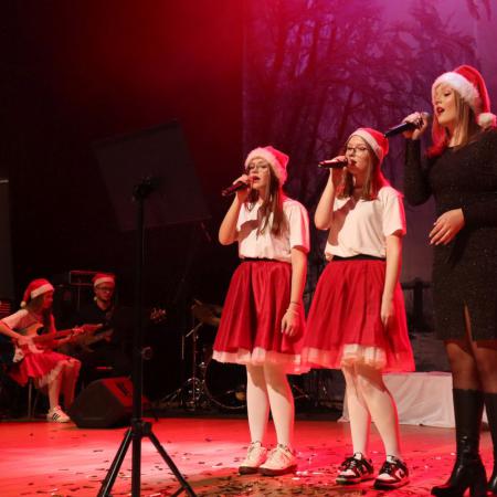 Dziewczyny w czapkach Mikołaja śpiewają na scenie 