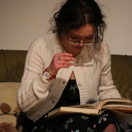 Kobieta w okularach siedzi na kanapie i czyta książkę