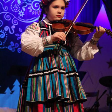 Dziewczynka w stroju ludowym gra na skrzypcach 