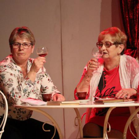 Dwie kobiety siedzące przy stoliku i pijące napoje z kieliszków