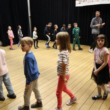 Dzieci na scenie tańczą w kółku 