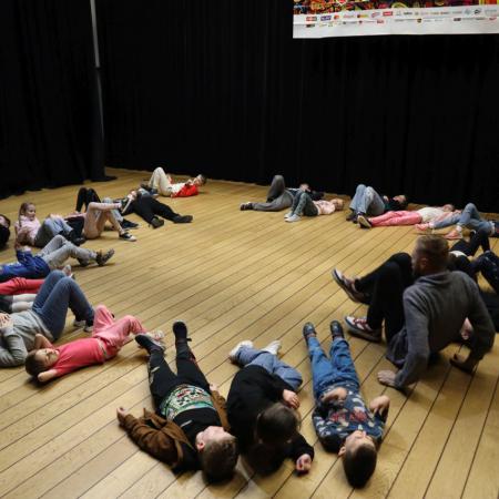Dzieci leżą w kółku na podłodze 