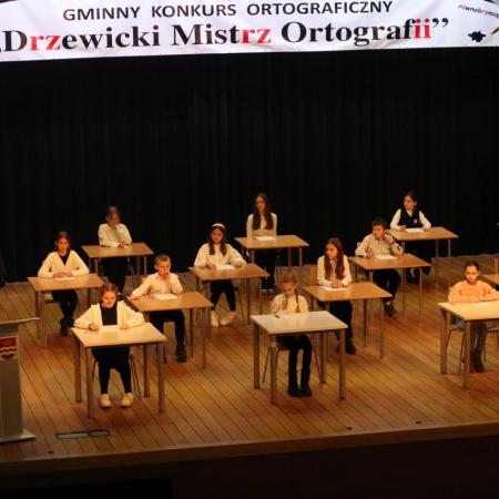 Uczestnicy konkursu ortograficznego piszący na scenie 