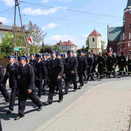 Grupa strażaków maszeruje pod pomnik 