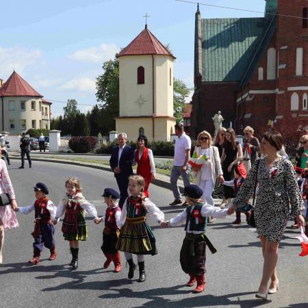 Dzieci w strojach ludowych maszerują pod pomnik 