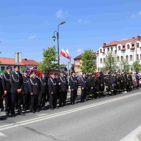 Strażacy stoją pod pomnikiem 