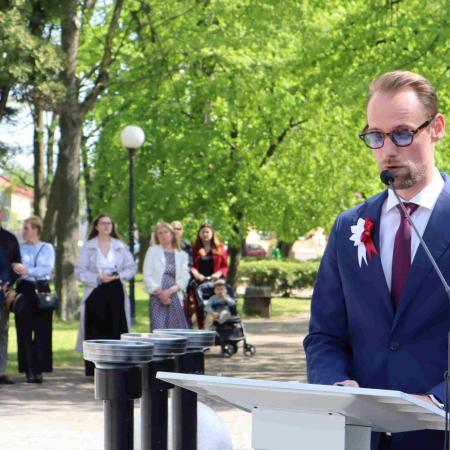 Mężczyzna wykonuje przemowę do osób pod pomnikiem 