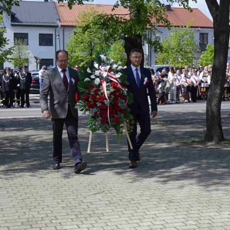 Dwaj mężczyźni składają wieniec pod pomnikiem 