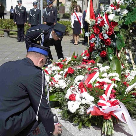 Strażak składa wieniec pod pomnikiem 