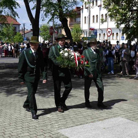 Trzech leśniczych niesie wieniec pod pomnik 