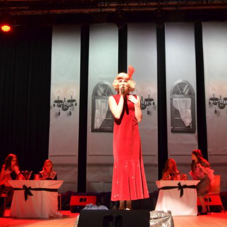 Kobieta w czerwonej sukni śpiewa do mikrofonu