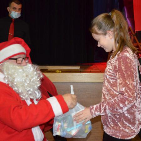 Mikołaj wręcza prezent dzieczynce w wieku szkolnym