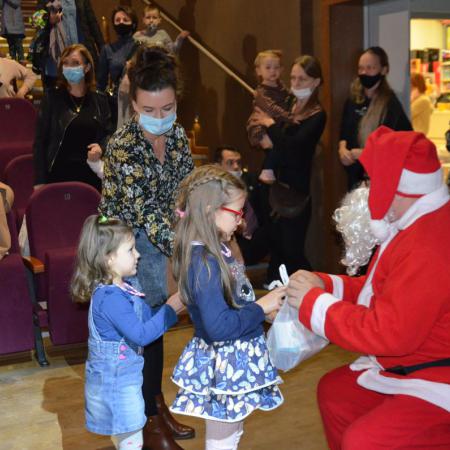 Mikołaj wręcza prezenty małym dziewczynkom i ich mamie