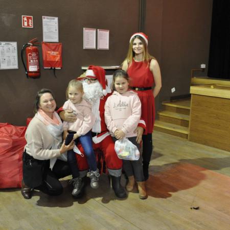 Mikołaj ze Śnieżynka trzyma dziewczynki na kolanach obok siedzi mama