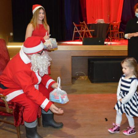 Mikołaj ze snieżynką wręczają prezent małej dziewczynce