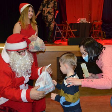 Mikołaj ze śnieżynką wręczają prezent małemu chłopczykowi i jego mamie