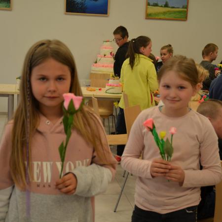 Na pierwszym planie dwie dziewczynki trzymające kwiay wykonane na warsztatach.