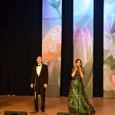 Trzech mężczyzn i kobieta w zielonej sukni śpiewają na scenie