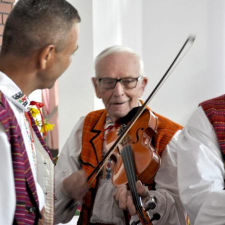 Trzej Panowie z zepołu ludowego , jeden z nich gra na skrzypcach.