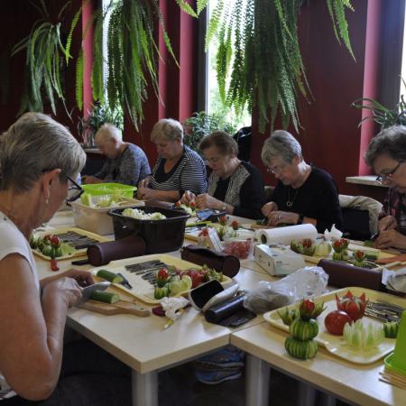 Uczestnicy warsztatów pracujący przy stole pełnym warzyw i owoców