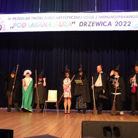 Uczestnicy WTZ w Lipinach stoją na scenie w przebraniach czarownic i czarodziei.